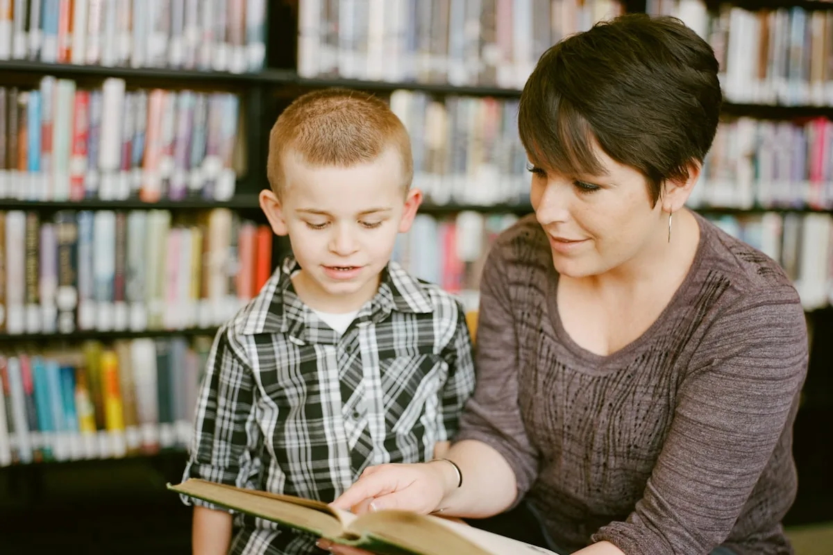 An adult and a child sitting together looking at a book