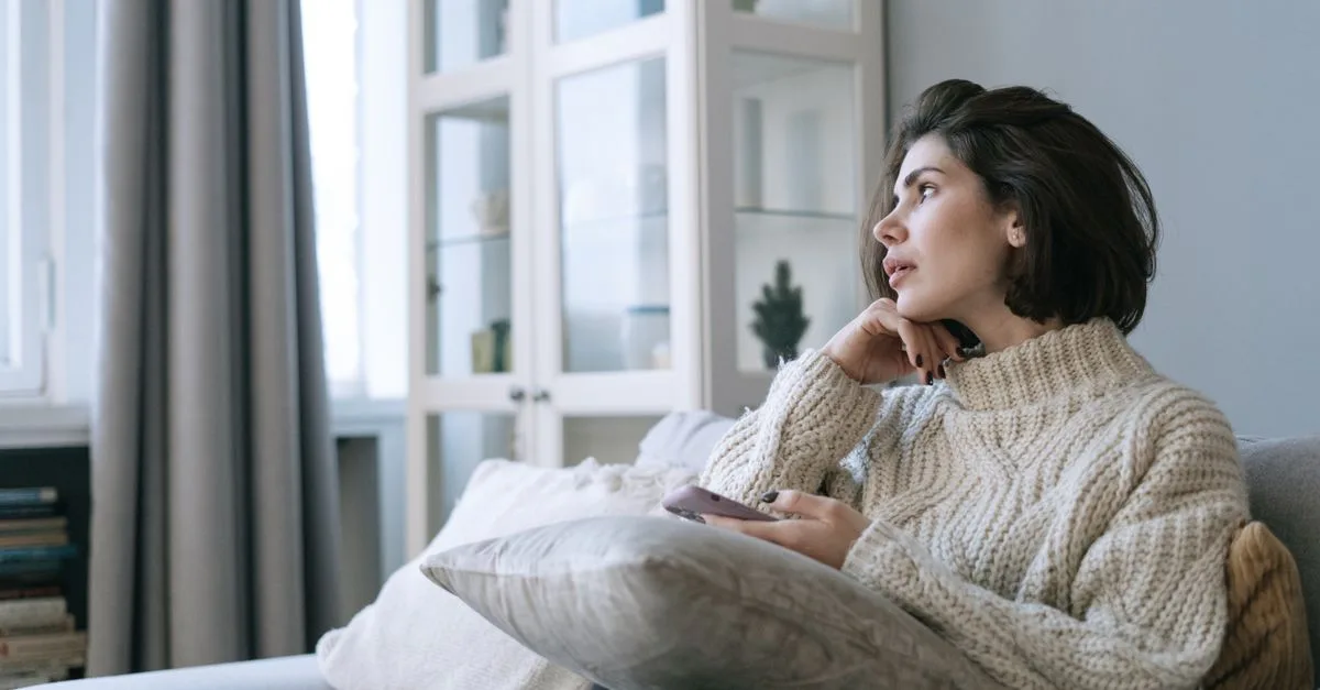 A woman sitting at home looking thoughtful