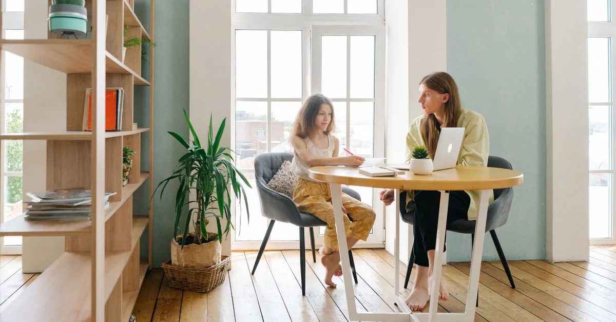 Two people sitting and talking together at a table in a bright room